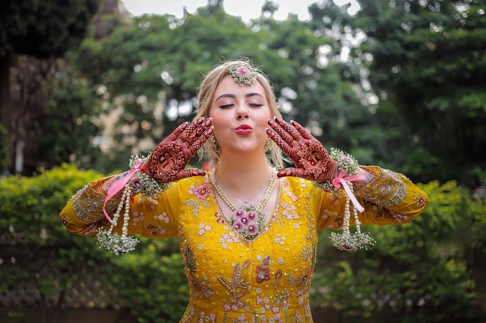 Bride in a yellow haldi outfit with fresh flower jewelry, hair and makeup by Eleglam