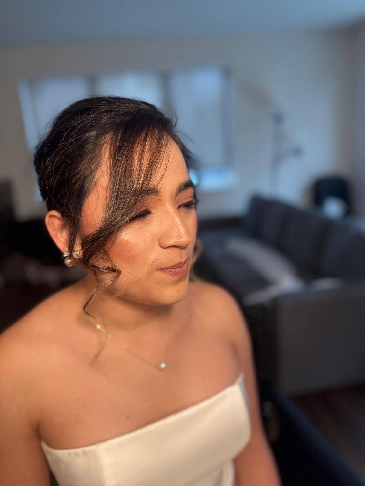 Bride in an ivory satin gown with a softly swept updo and luminous cheek, hair and makeup by Eleglam
