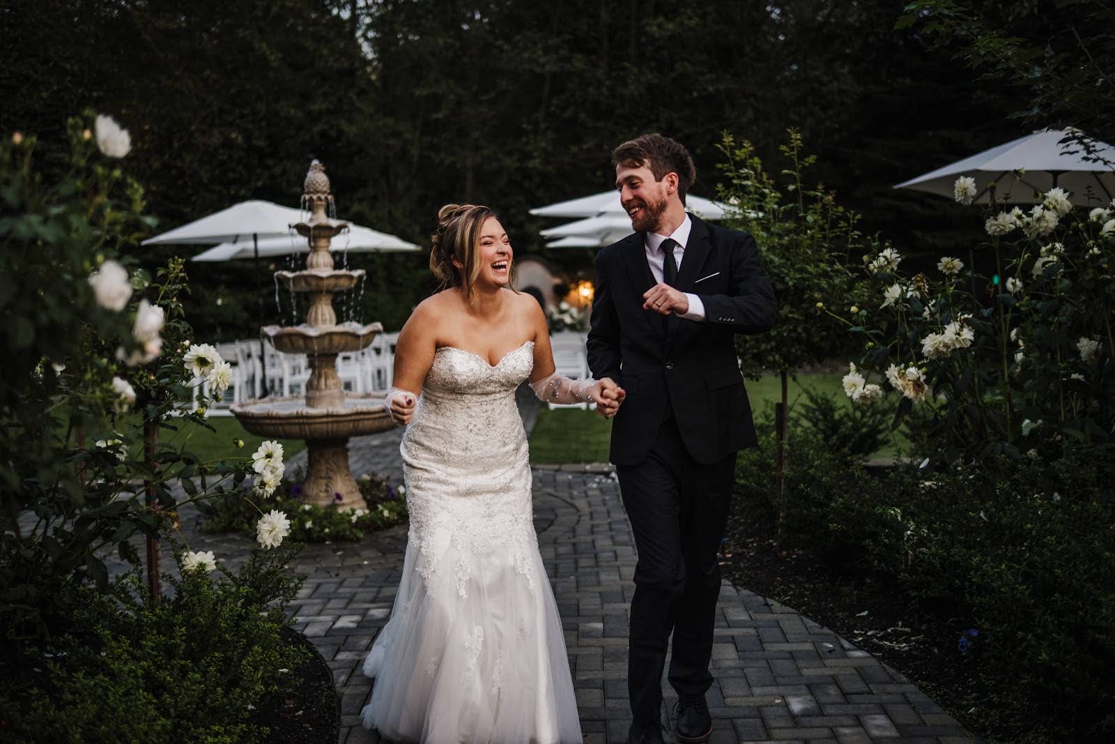 Bride and groom laughing beside a fountain at a Seattle garden wedding venue, bridal hair and makeup by Eleglam