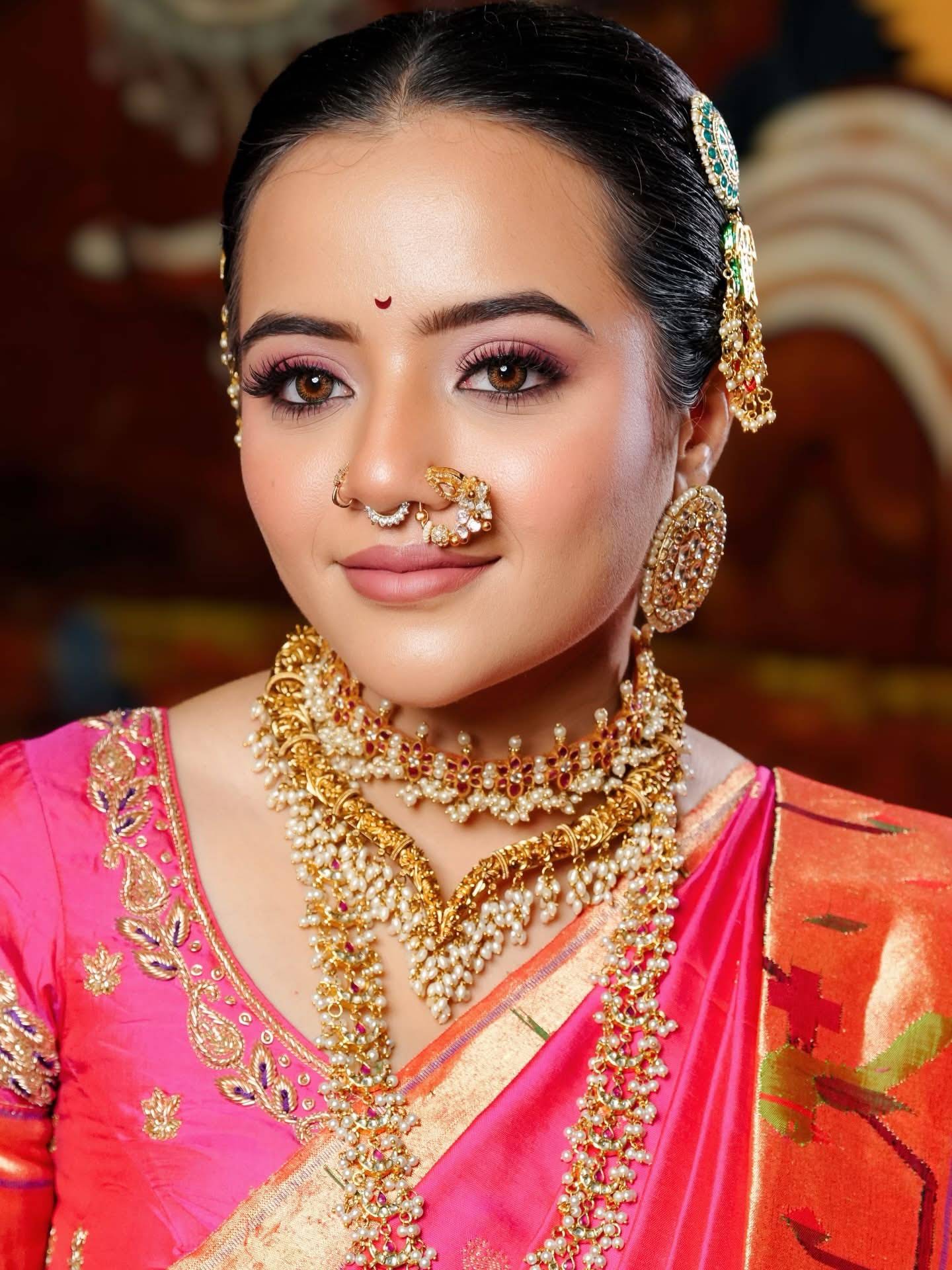 South Indian bride in a pink saree with gold temple jewelry and nath, makeup by Eleglam